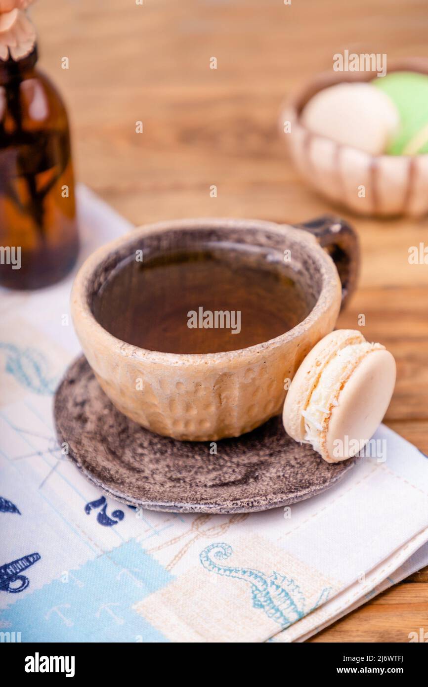 Tasse en céramique avec thé et macaron sur une table en bois, espace copie Banque D'Images