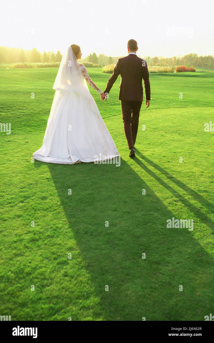 couple de mariage (femme et homme) en robe de mariage et costume marchant sur le terrain. L'amour, la famille, la tendresse concept Banque D'Images