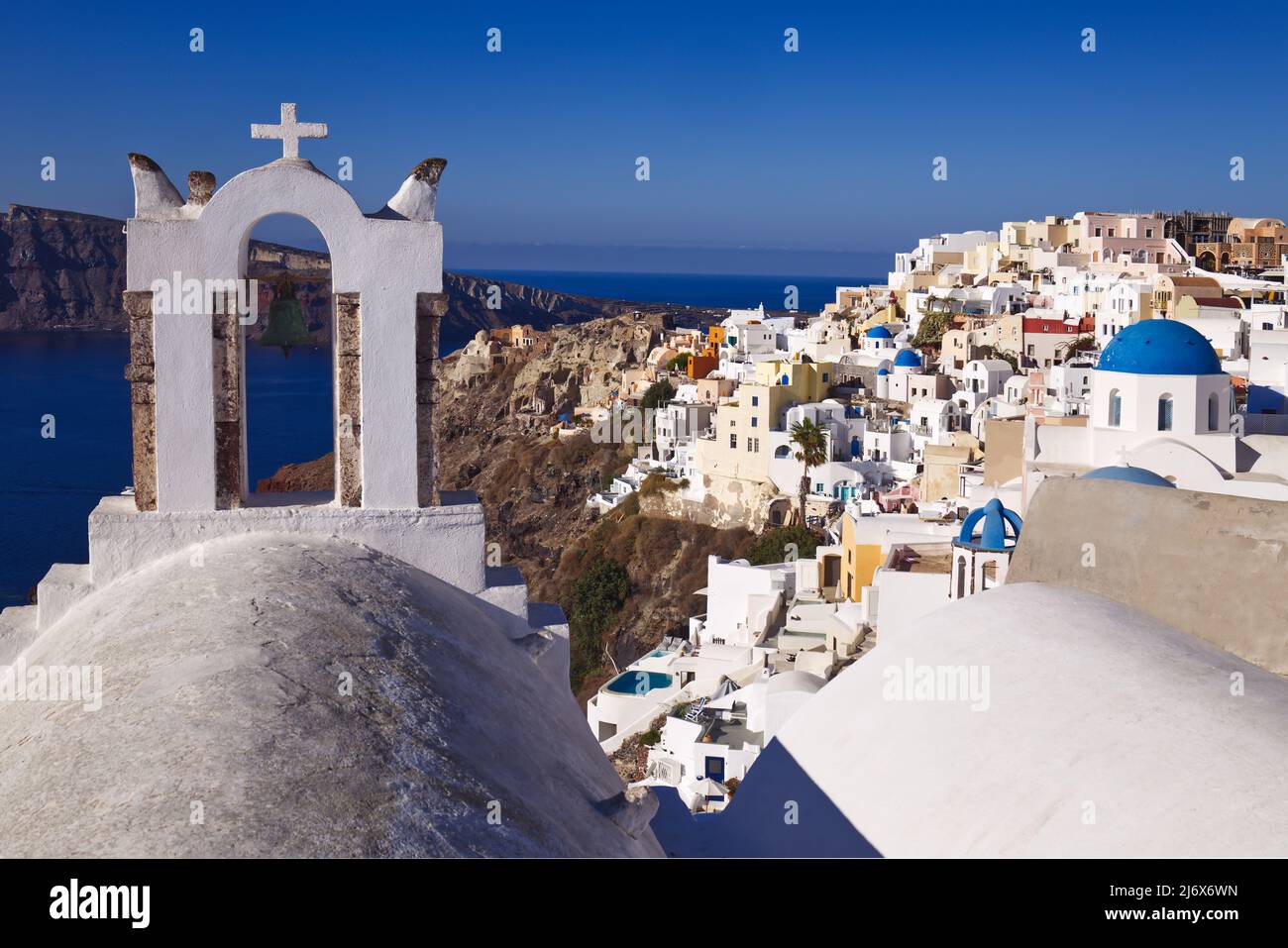 Oia, Santorini, Iles grecques, Grèce - clocher, églises avec dômes bleus, maisons, magasins et autres bâtiments blancs sur la falaise sous un soleil éblouissant Banque D'Images