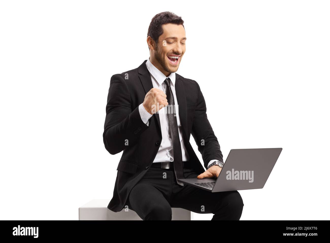 Homme d'affaires assis et utilisant un ordinateur portable et gesturant le bonheur isolé sur fond blanc Banque D'Images