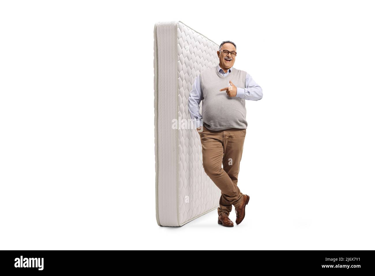 Homme mûr se penchait sur un matelas de lit isolé sur fond blanc Banque D'Images