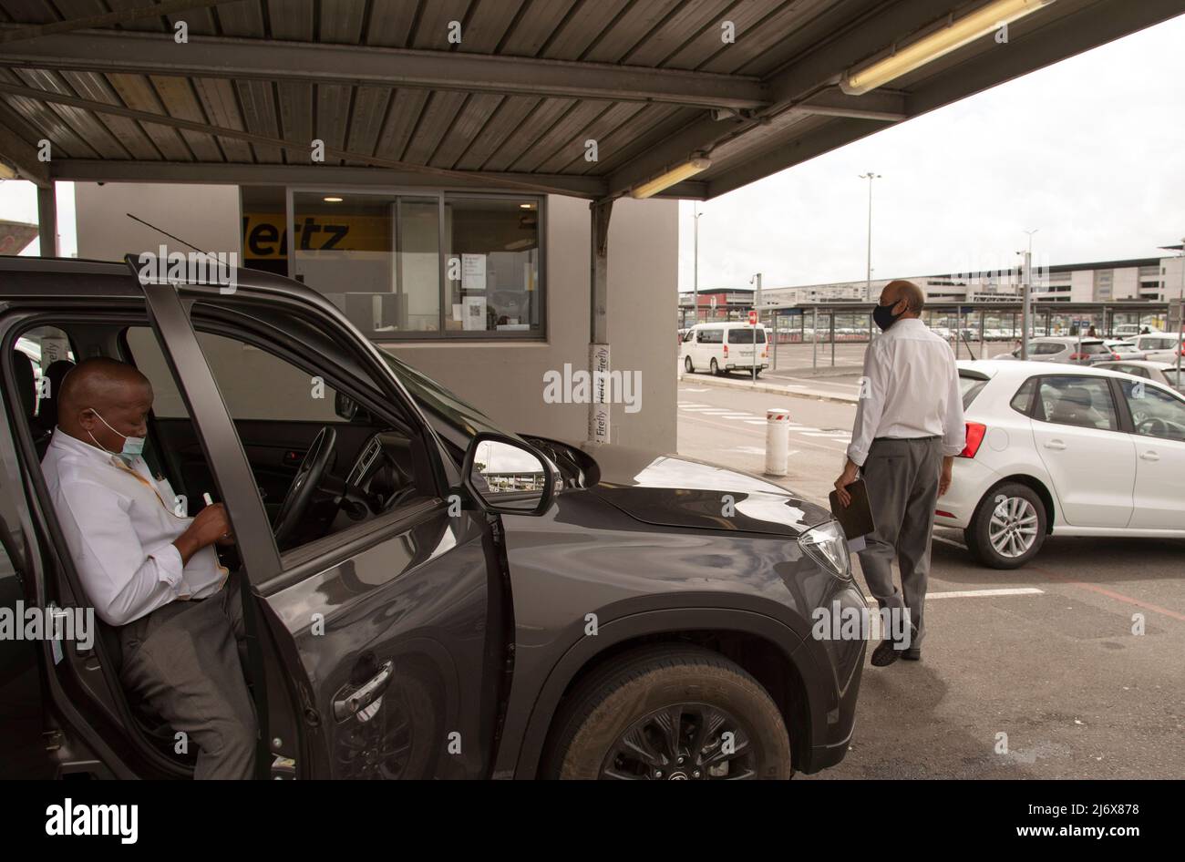 Le Cap, Afrique du Sud. 2022. Location de voiture à l'aéroport renvoie un employé vérifiant une voiture noire qui vient d'être retournée au dépôt. Banque D'Images Le Cap, Afrique du Sud. 2022. Location de voiture à l'aéroport renvoie un employé vérifiant une voiture noire qui vient d'être retournée au dépôt. Banque D'Images