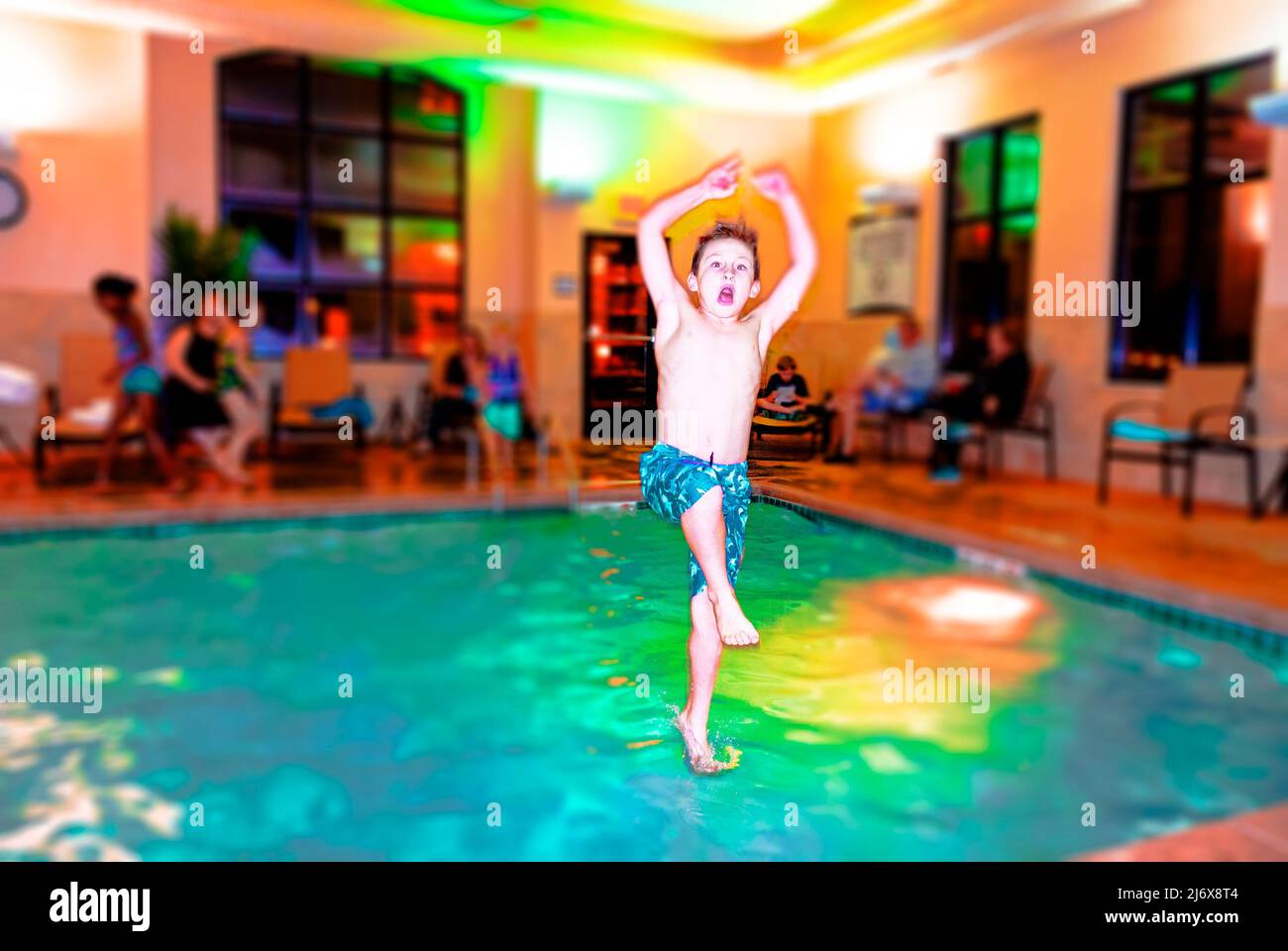 Un garçon de neuf ans se retrouvant dans une piscine intérieure de motel près de Carmel, Indiana, États-Unis. Banque D'Images