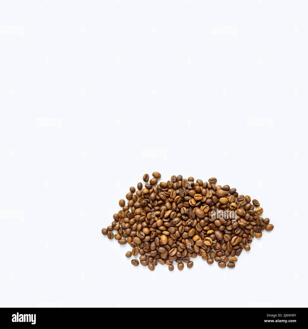 Tas de grains de café torréfiés sur blanc avec espace de copie. Image détaillée des grains de café. Banque D'Images