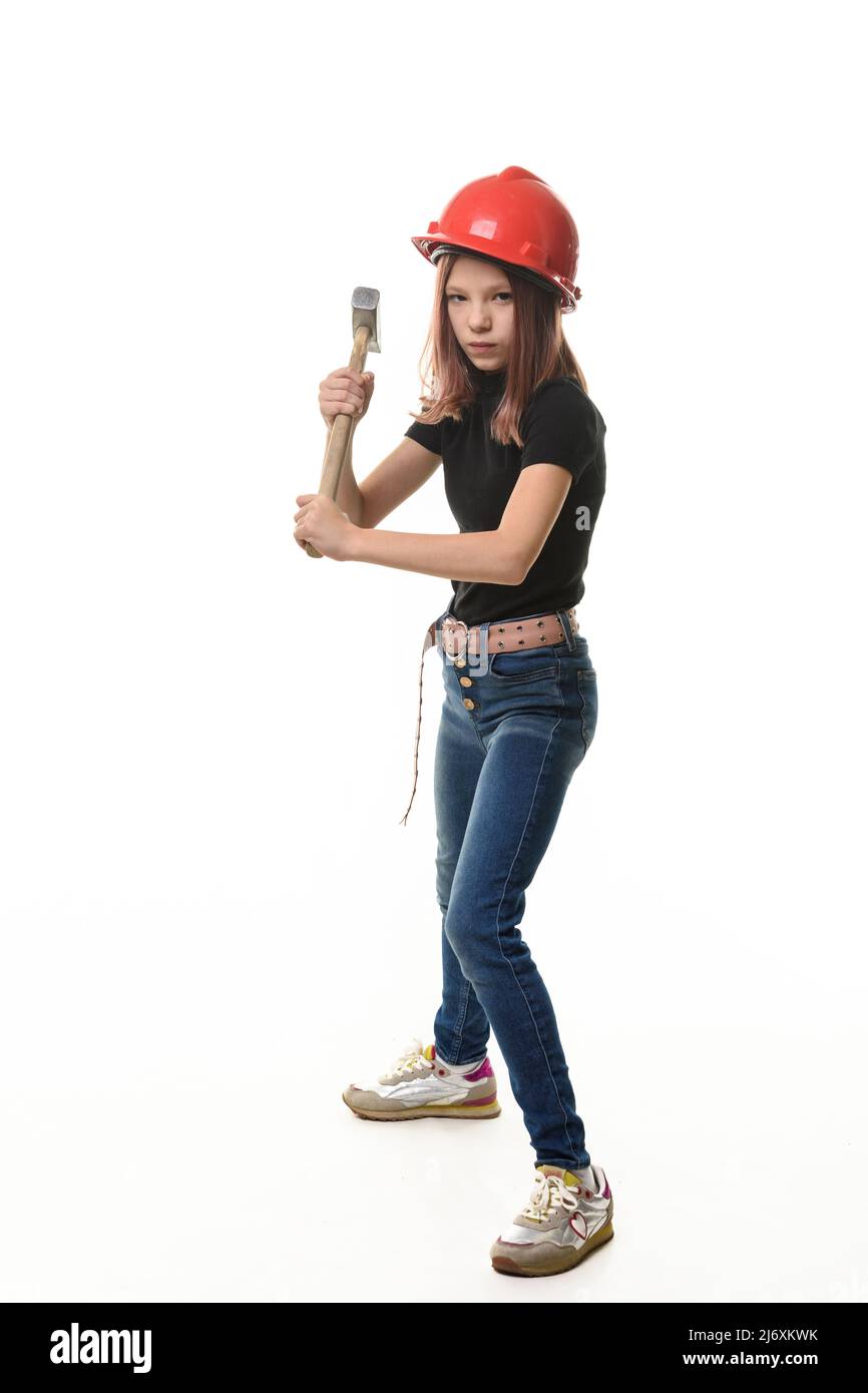 Une fille dans un casque dur se prépare à frapper avec un marteau, isolé sur un fond blanc Banque D'Images