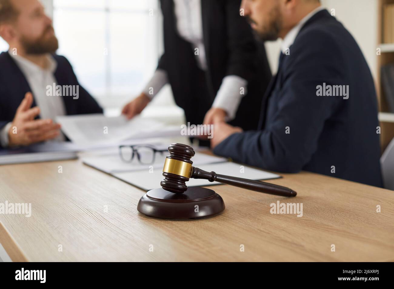 Le gavel du juge sur une table en bois, et les personnes qui travaillent avec des documents en arrière-plan Banque D'Images