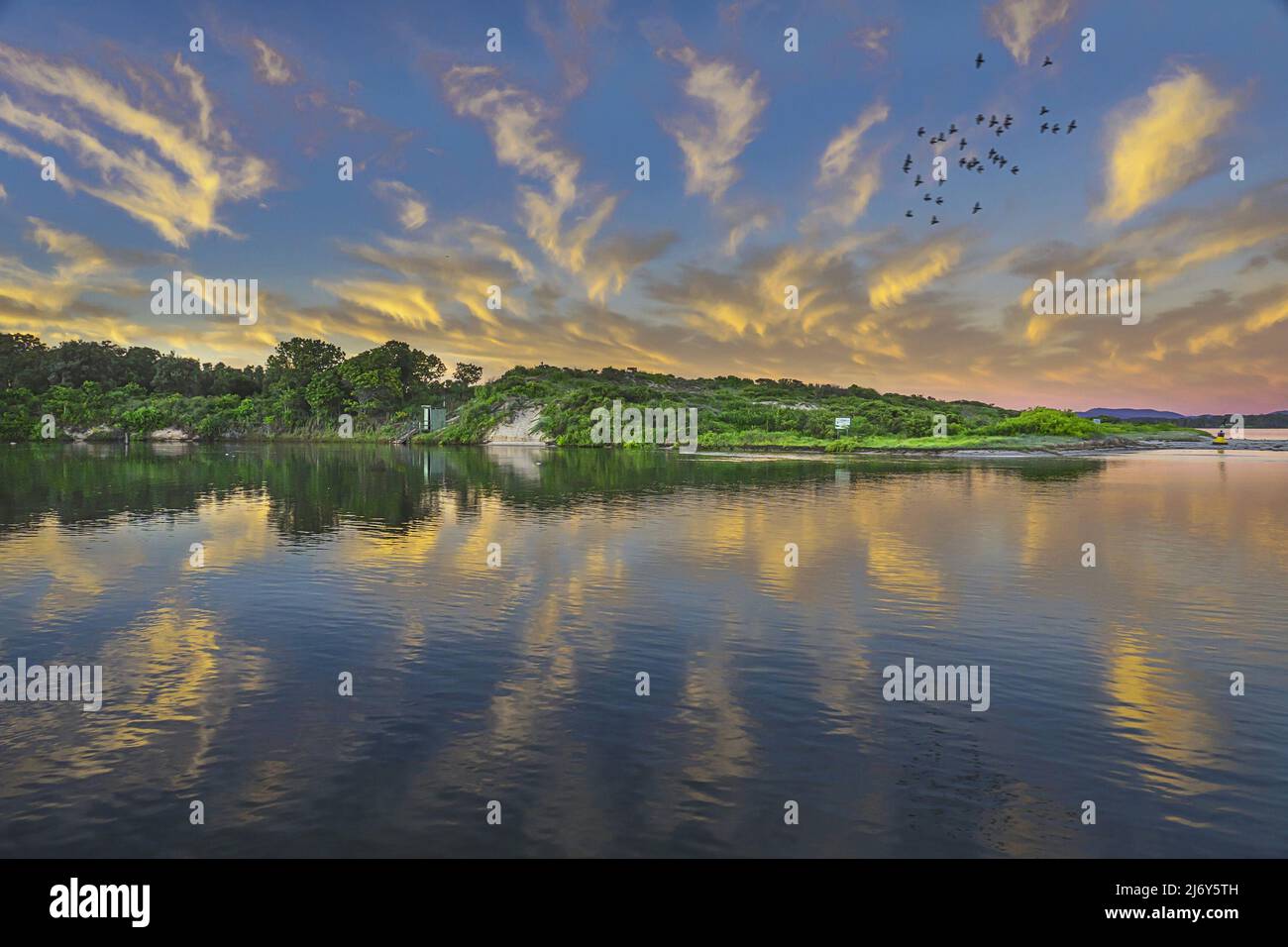 Lac Wallis au lever du soleil avec des nuages reflétés dans la surface fixe de l'eau. Forster Tuncurry, Nouvelle-Galles du Sud, Australie Banque D'Images