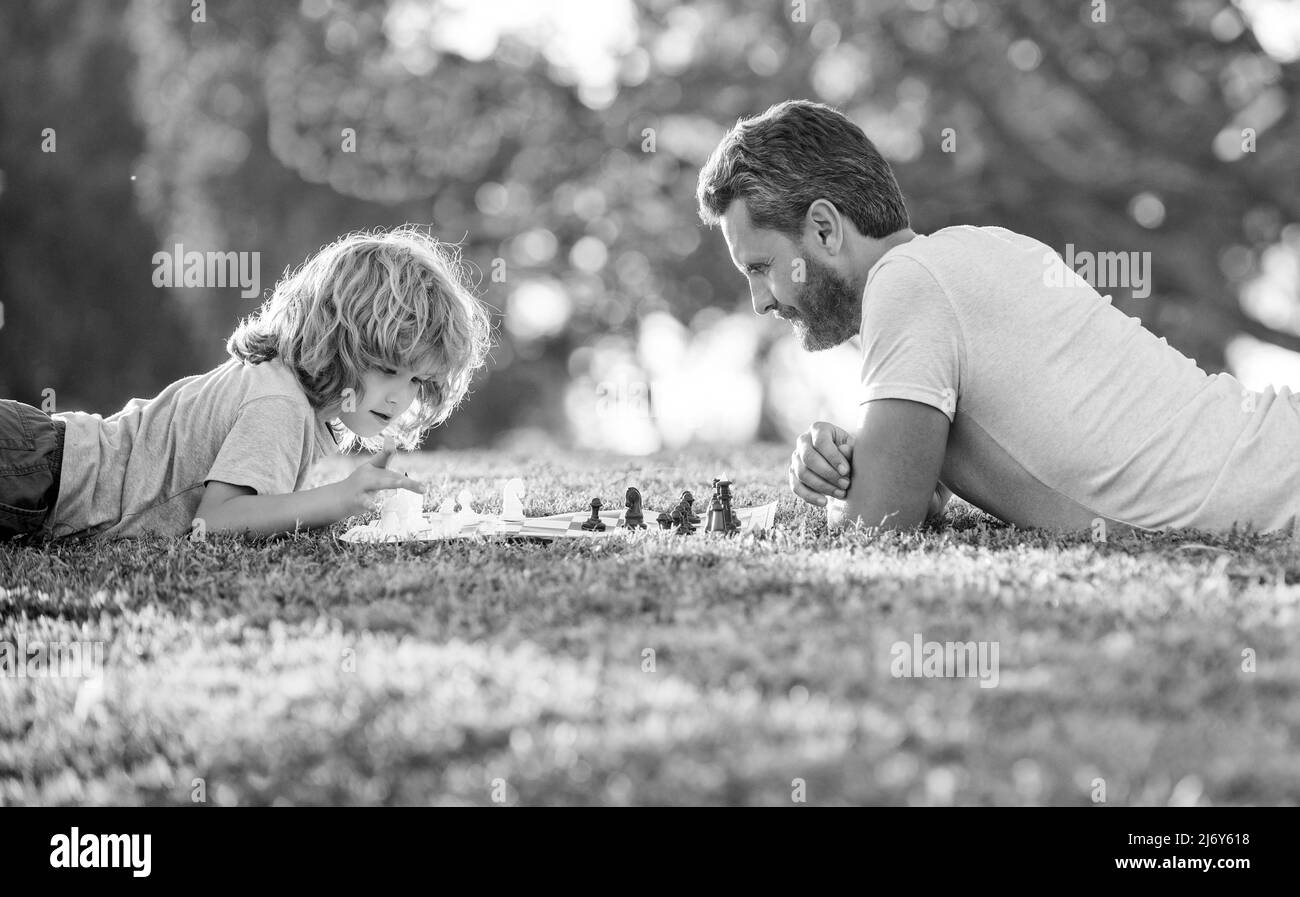 bonne famille de papa et fils enfant jouant aux échecs sur l'herbe verte dans le parc en plein air, jouant aux échecs Banque D'Images