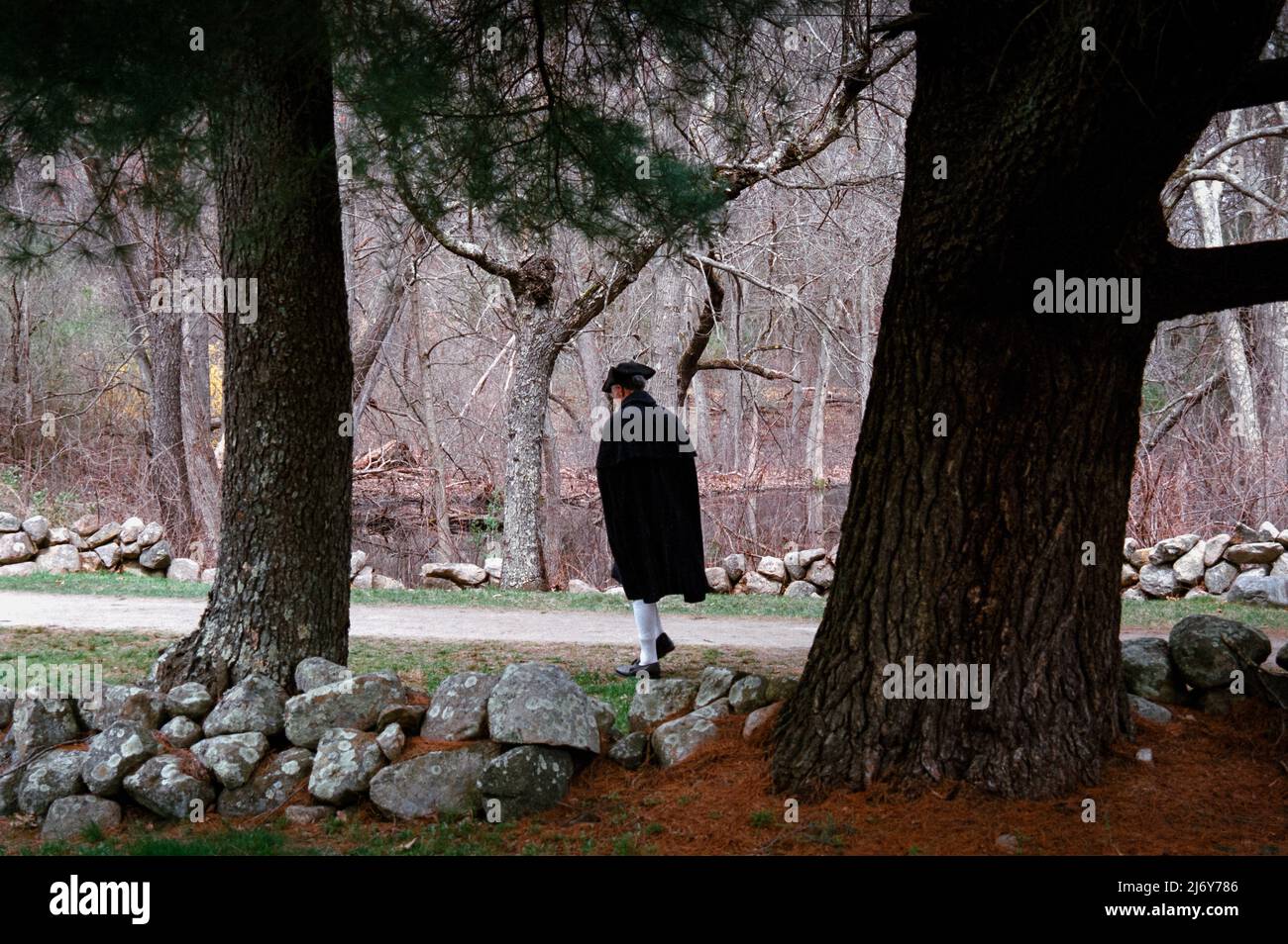 Un personnage unique de reconstitution se promène entre les arbres le long de Battle Road, devant les troupes à Lexington, Massachusetts, pendant le week-end du jour des Patriots. Env Banque D'Images