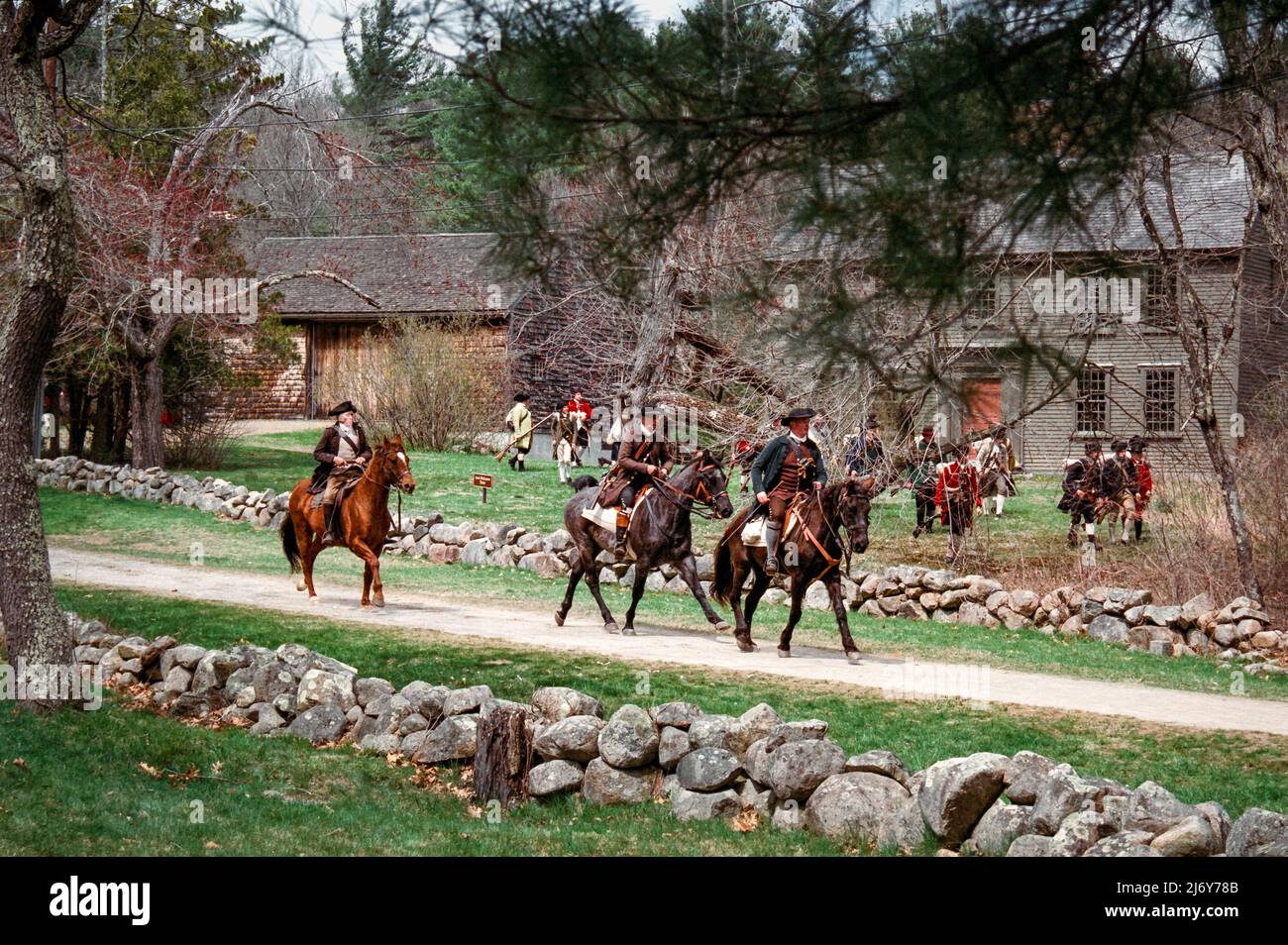 Les personnages de la reconstitution de Minuteman longent des chevaux sur Battle Road, devant des troupes à Lexington, Massachusetts, pendant le week-end du jour des Patriots. Capturé o Banque D'Images