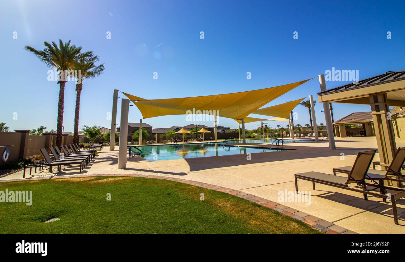 Des canapés jaunes offrent de l'ombre sur la piscine communautaire Banque D'Images