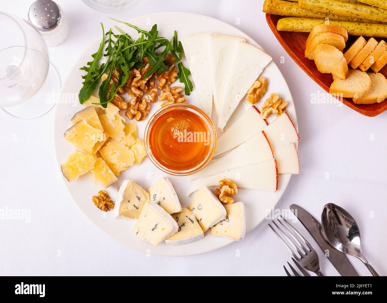 Différents types de fromage tranchés et servis sur une assiette avec un bol de miel, des noix Banque D'Images