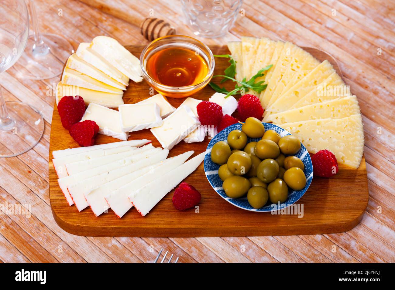 Différents types de fromage, miel, framboises et olives sur bois Banque D'Images