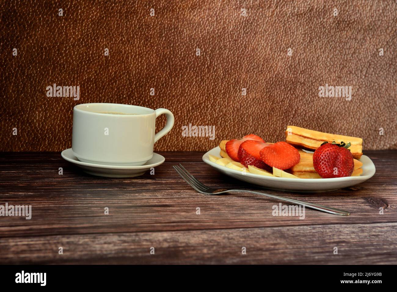 Gaufres belges avec fraises et bananes avec une tasse de café noir sur une table en bois. Gros plan. Banque D'Images