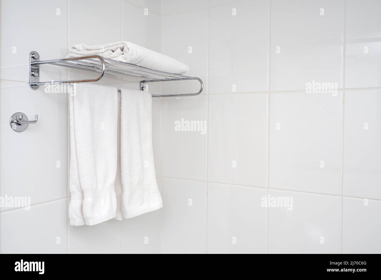 Intérieur de la salle de bains avec étagère en fer et serviettes douces. Carrelage blanc avec composition minimale dans la salle de bains. Banque D'Images