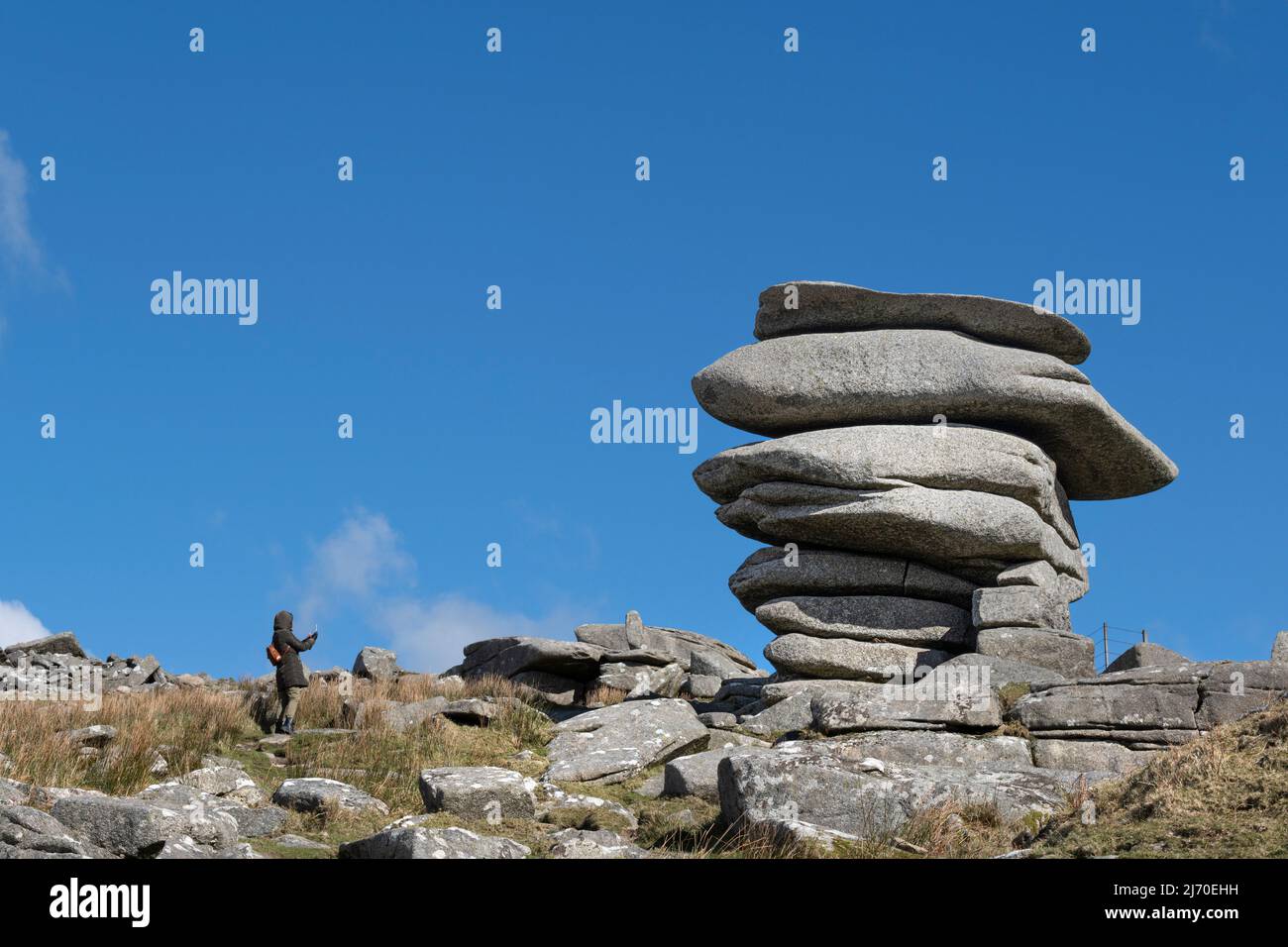 Un marcheur photographiant le Cheesewring une énorme pile de roches de granit formée par l'action glaciaire sur le sommet de Stowe Hill sur Bodmin Moor en Cornouailles. Banque D'Images