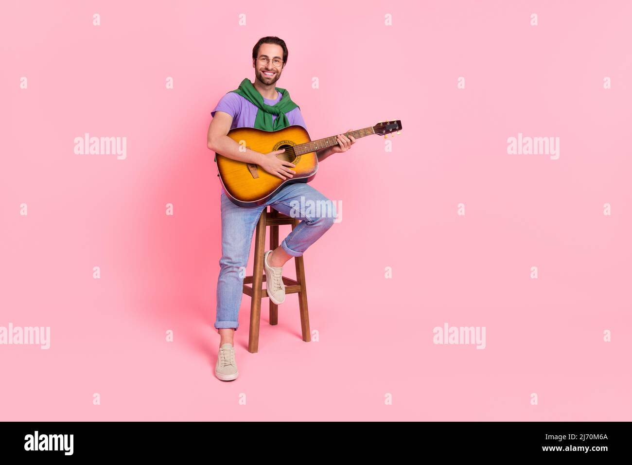 Image du corps entier d'un beau petit ami attrayant jouant sérénade pour sa petite amie isolée sur fond de couleur rose Banque D'Images