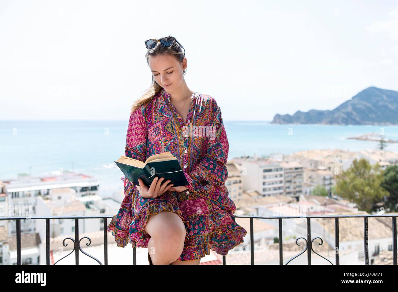 jeune femme sur le balcon avec livre et vue sur la mer Banque D'Images