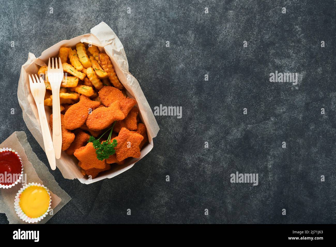 Fish and Chips, restauration rapide britannique. Bâtonnets de poisson avec frites sur une plaque de papier à emporter sur fond de béton ancien sombre. Traditionnel anglais authe Banque D'Images