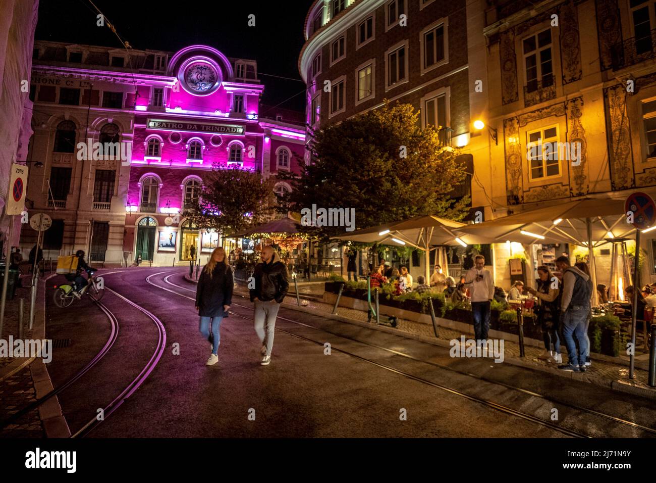 Piétons marchant la nuit devant le Teatro da Trindade, Lisbonne, Portugal Banque D'Images