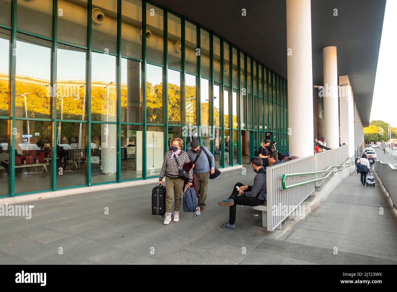 Touristes personnes avec des valises bagages dans le visage masques marchant à la sortie de la Plaza de Armas gare routière à Séville, Espagne Banque D'Images