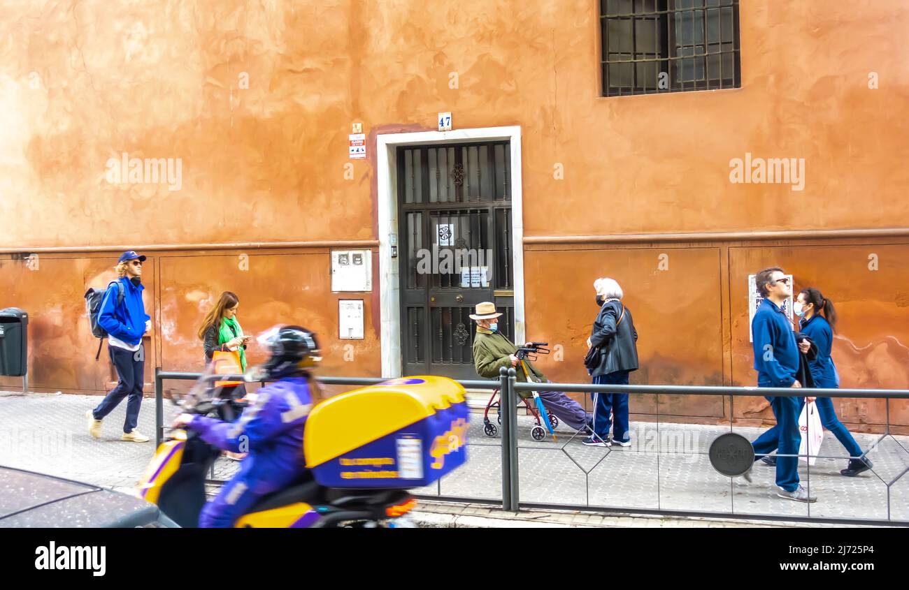 Assistanthelping déplacer une personne âgée sur un fauteuil roulant sur un dispositif de mobilité dans la rue de Séville à Triana, Espagne Banque D'Images