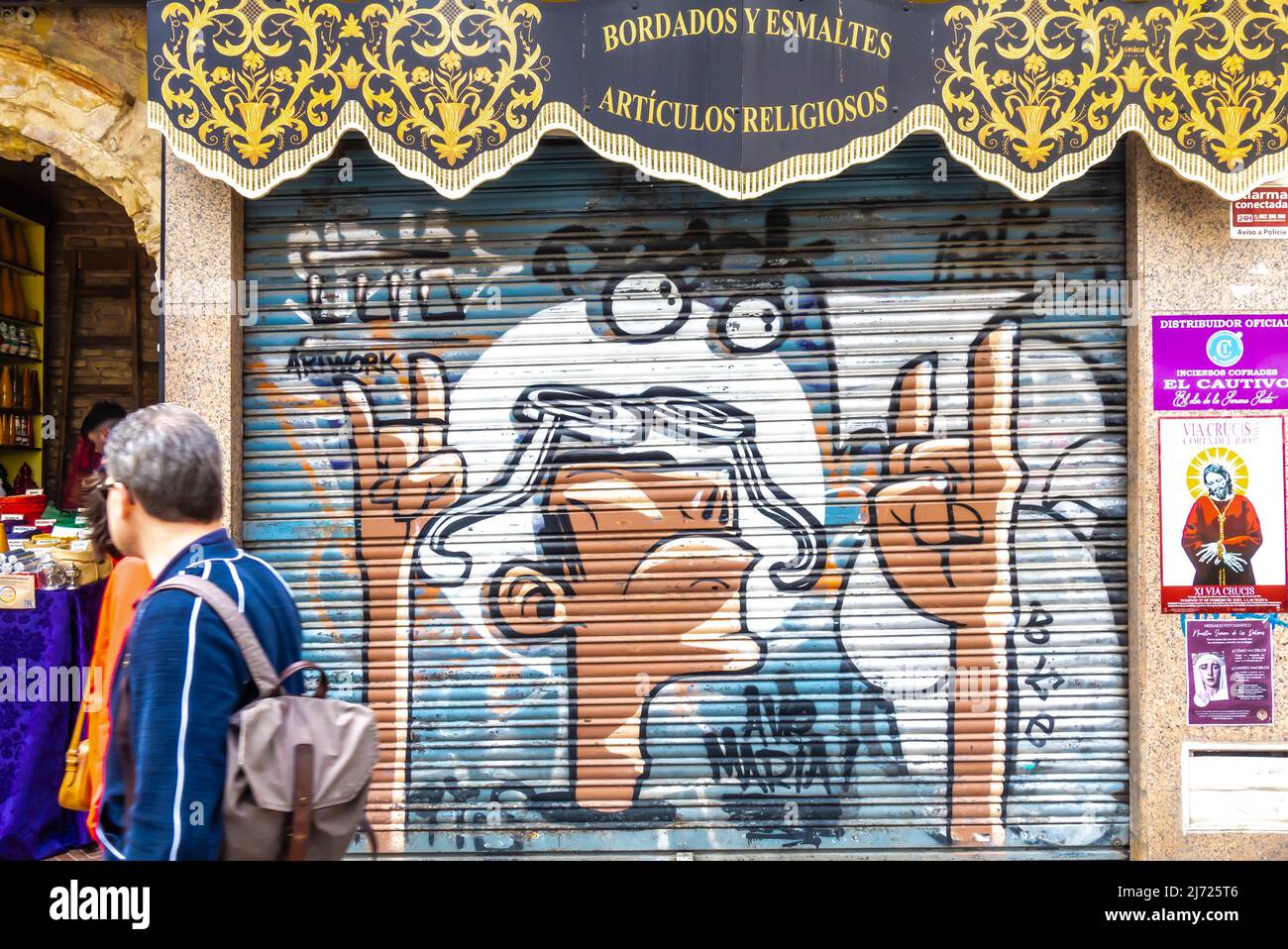 Fresque sur la porte boarée représentant un homme avec des mains avec un signe de chèvre sur le magasin Bordados y Esamaltes, Madrid, Espagne Banque D'Images