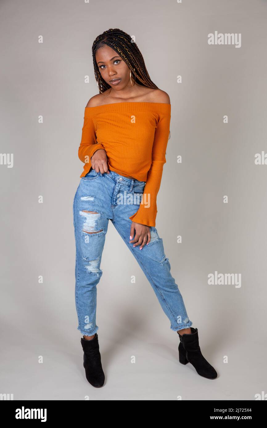 Portrait d'une jeune femme noire avec orange vintage top et jeans baggy  posant sur un fond blanc Photo Stock - Alamy
