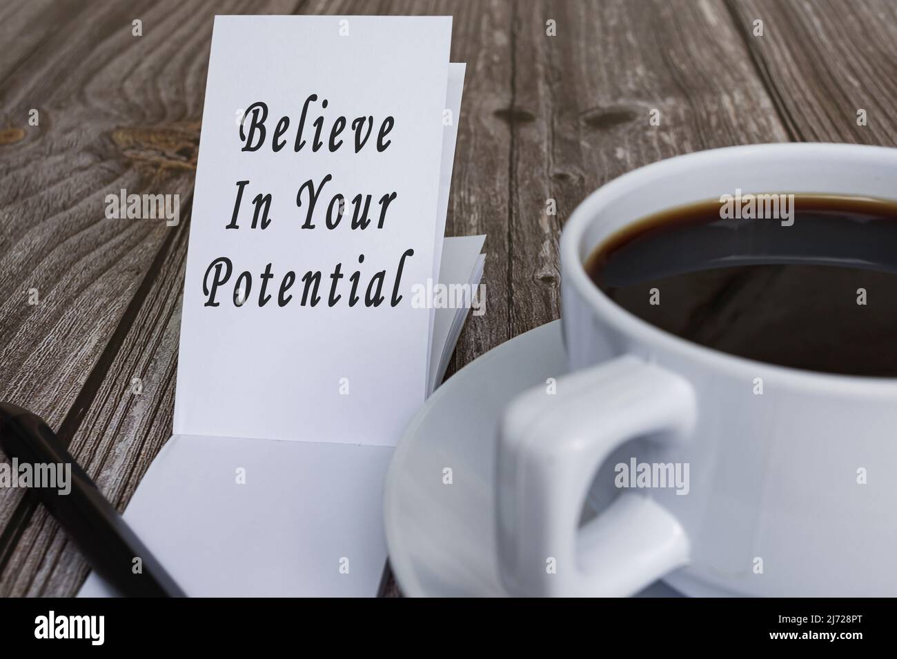 Citations motivantes et inspirantes sur le bloc-notes avec une tasse de café sur un bureau en bois - croyez en votre potentiel. Banque D'Images