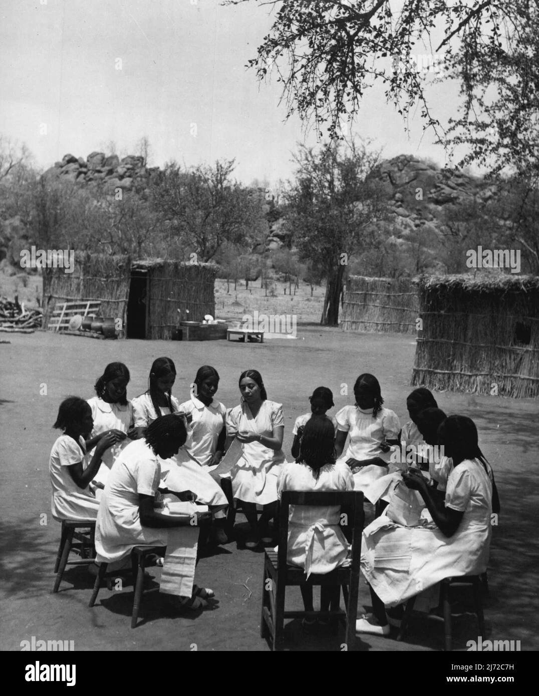 Les filles soudanaises train pour être enseignants. Ils apprennent dans les salles de classe de Grass Hut jusqu'à ce que le New College soit prêt. La classe de couture est assise dans un cercle autour de l'enseignant à l'extérieur des huttes d'herbe qui ont été mises en place comme des salles de classe temporaires. Ces huttes, ou tukls, sont érigées par des soudanais en quelques heures. 14 mai 1953. (Photo du Bureau central d'information). Banque D'Images