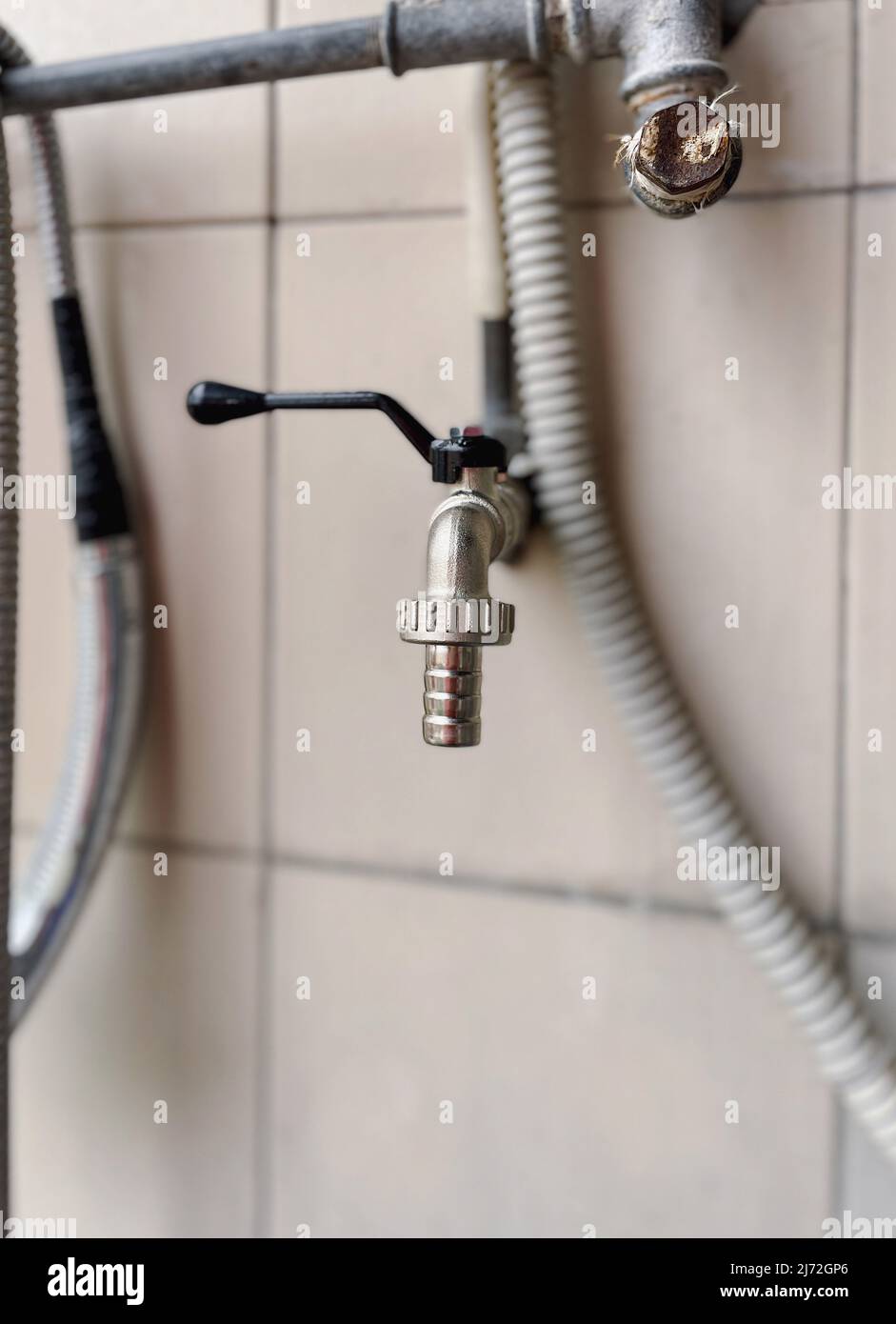 Robinet d'eau extérieur en métal récemment installé robinet en acier inoxydable pour les jardins reliés à de vieux tuyaux. Banque D'Images