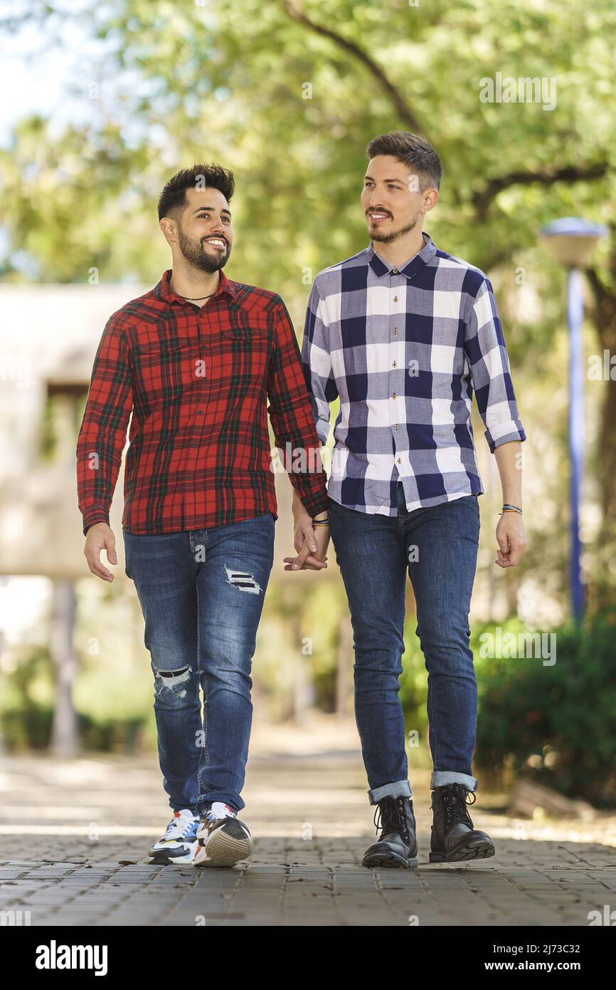 un couple gay heureux se promenant dans la rue en tenant les mains Banque D'Images