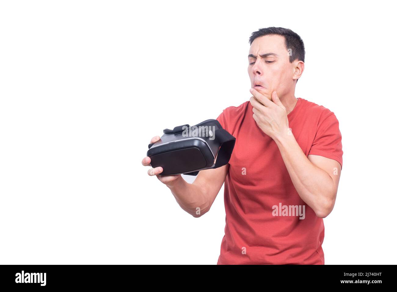 Homme perplexe regardant des lunettes VR en studio Banque D'Images