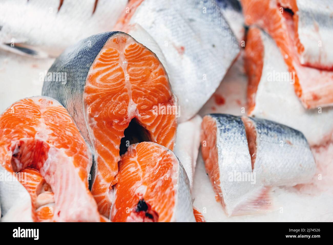 Truite, coupée en morceaux, posée sur la glace sur le comptoir du magasin. Morceaux de poisson rouge en gros plan. Banque D'Images