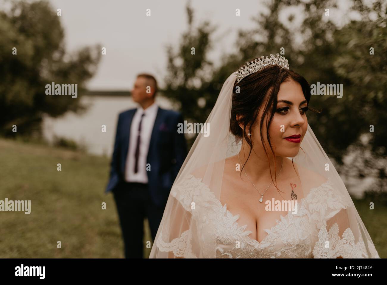 Jeune homme caucasien européen marié en costume bleu et femme à cheveux noirs mariée en robe de mariage blanche avec voile long et tiara sur la tête. Look newlyweds Banque D'Images