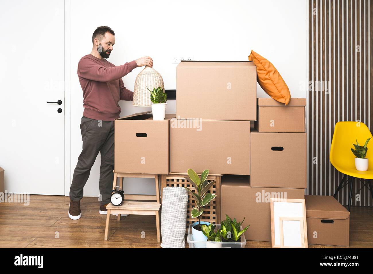 Homme mature déballant des choses des boîtes tout en déplaçant dans nouvel appartement non meublé. Banque D'Images