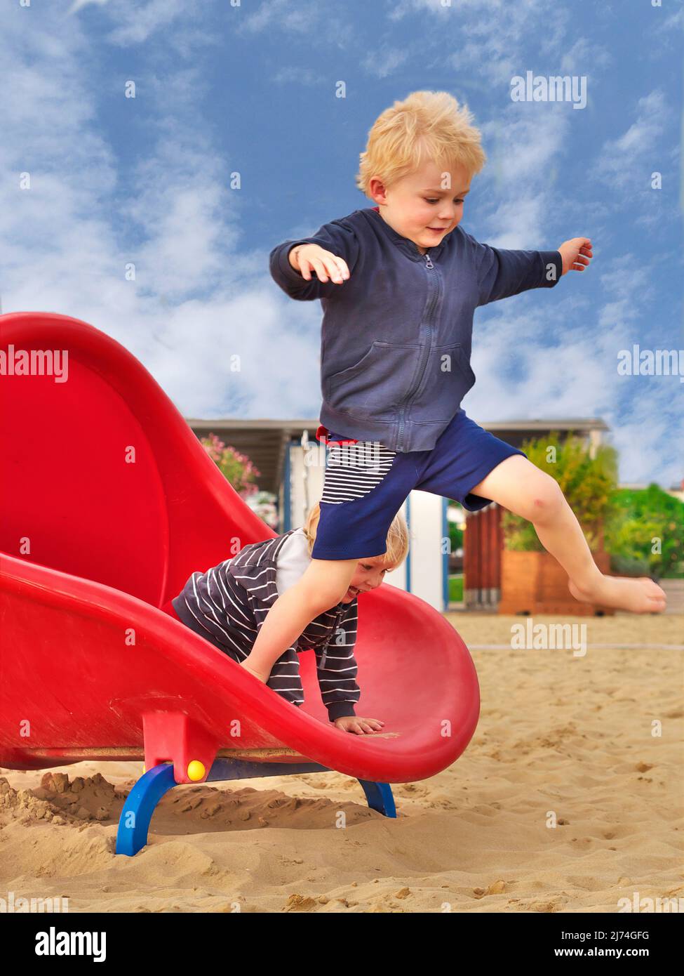 la photo montre un garçon qui saute d'un toboggan; le toboggan est près de la plage Banque D'Images