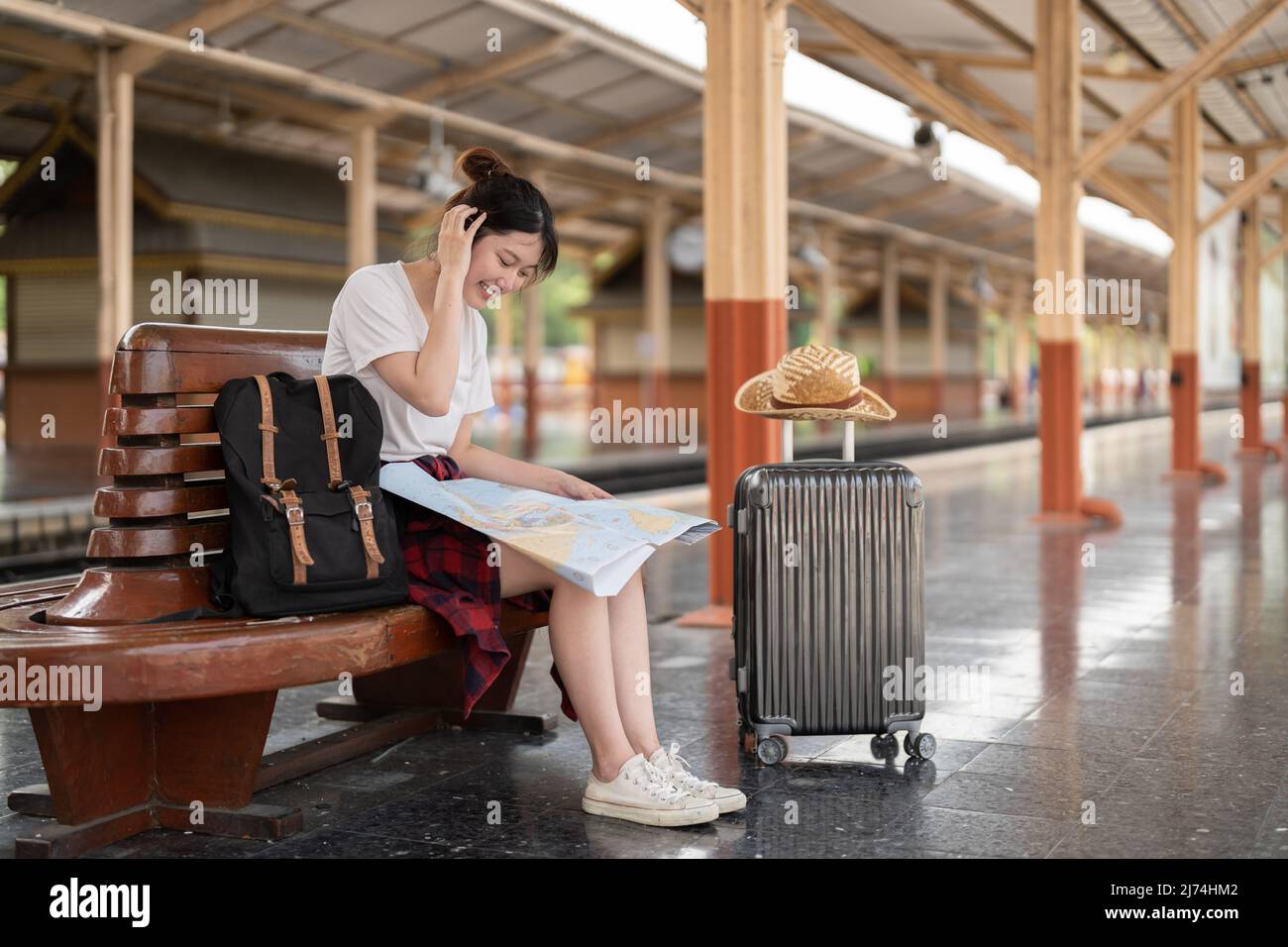 jeune femme asiatique voyageur assis avec une carte choisissez où voyager et sac en attente de train à la gare, concept de voyage d'été Banque D'Images