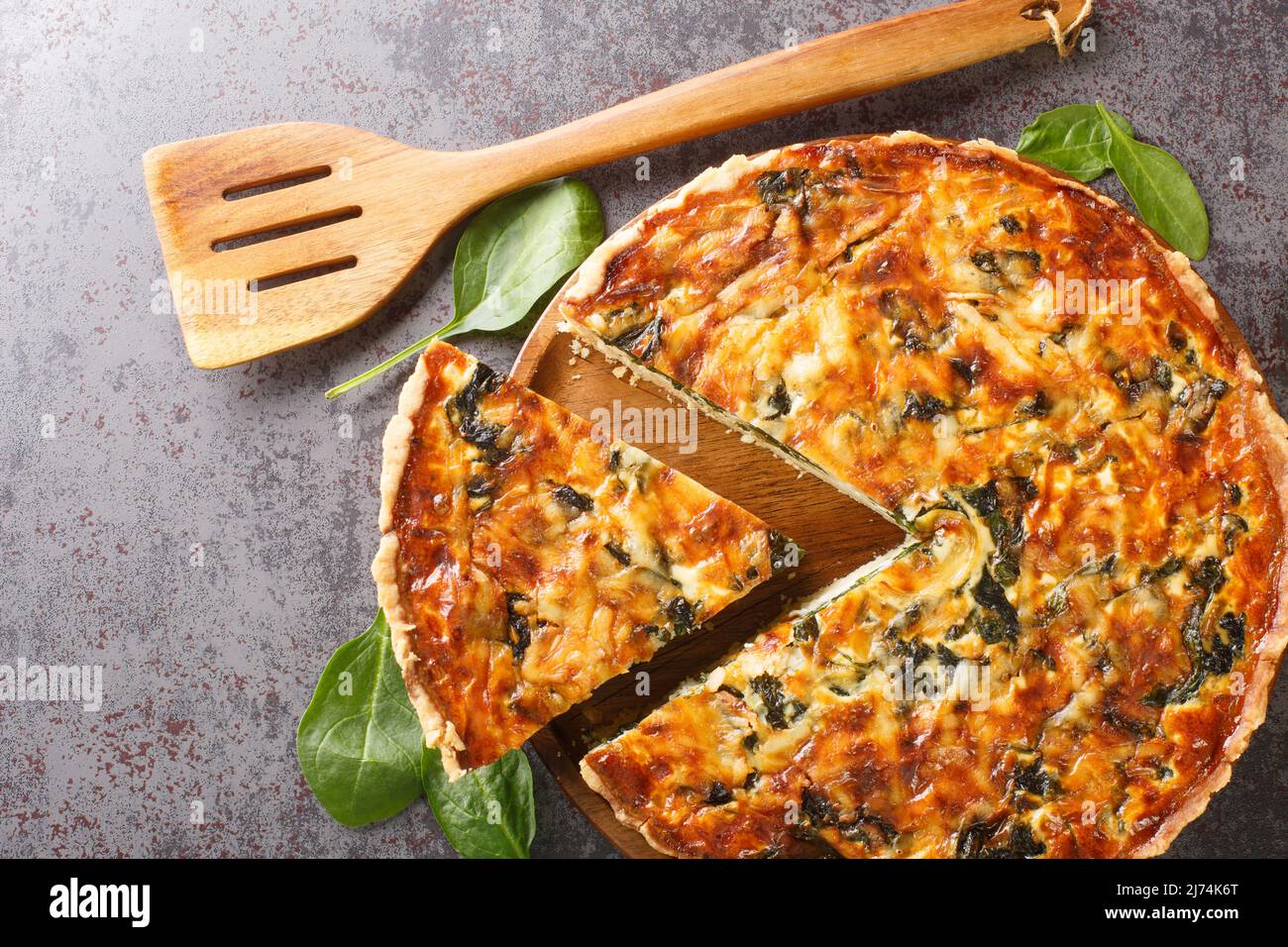 La quiche florentine est une quiche d'épinards frais cuite dans une croûte de tarte maison pour servir pour le brunch ou le petit déjeuner pour le dîner sur table grise gros plan. Hetizont Banque D'Images