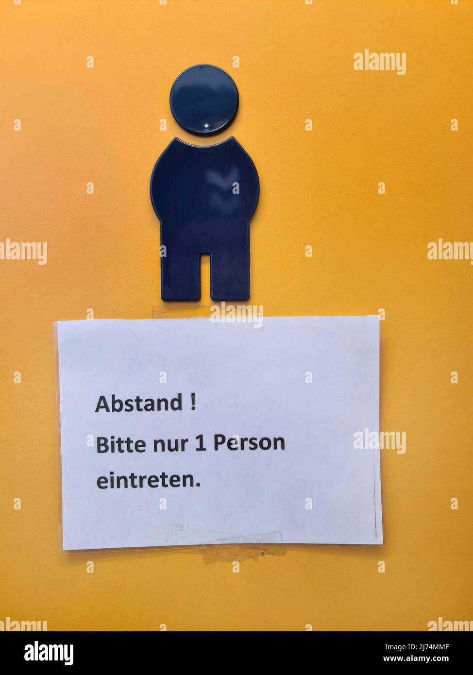 Note avec l'inscription « Distance! Veuillez entrer seulement 1 personnes' est accrochée sur la porte des toilettes de la chambre pour hommes, Allemagne Banque D'Images