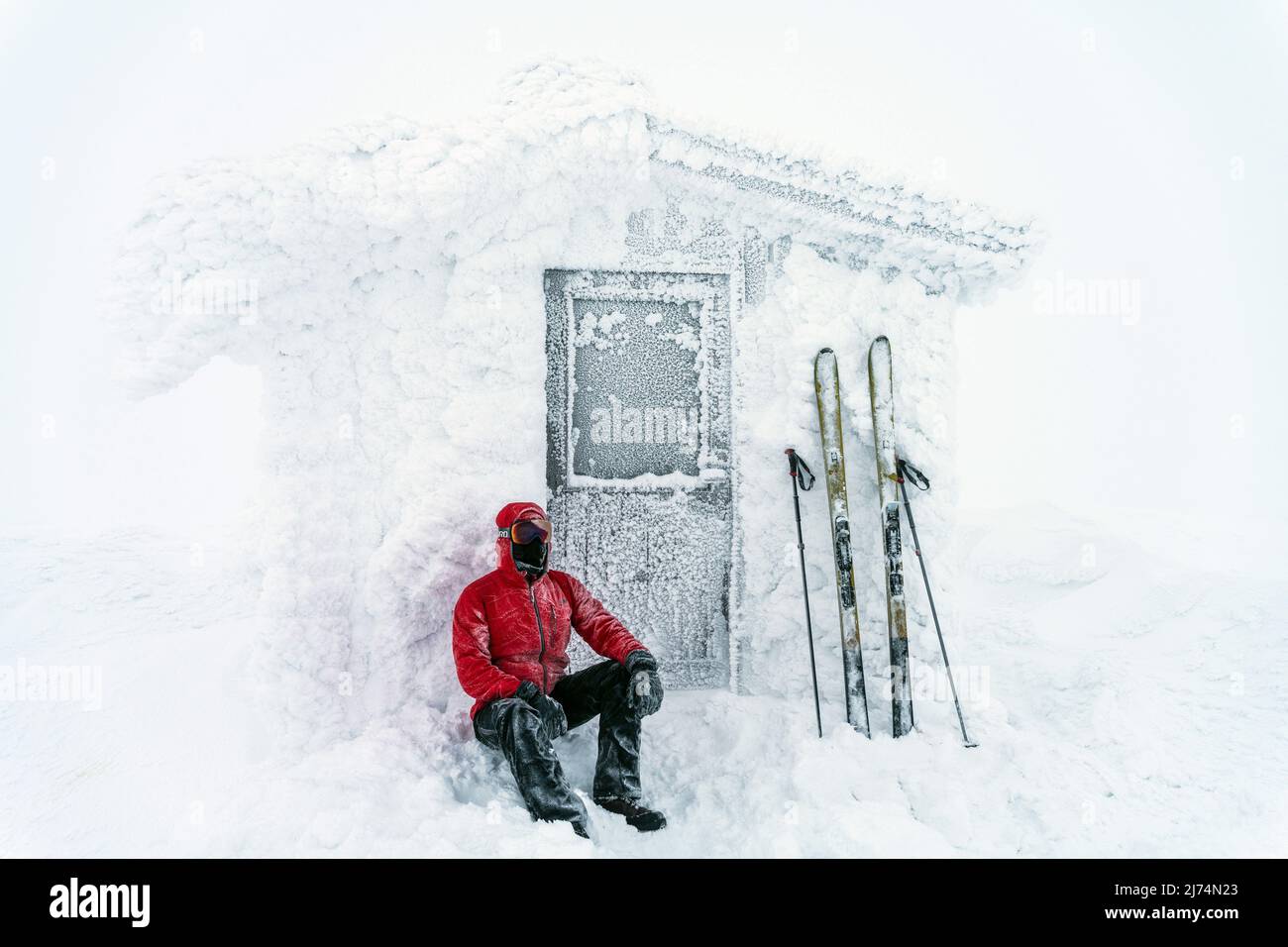 Skieur devant une cabane enneigée en hiver, Suède, Laponie, Dundret Naturesvat Banque D'Images