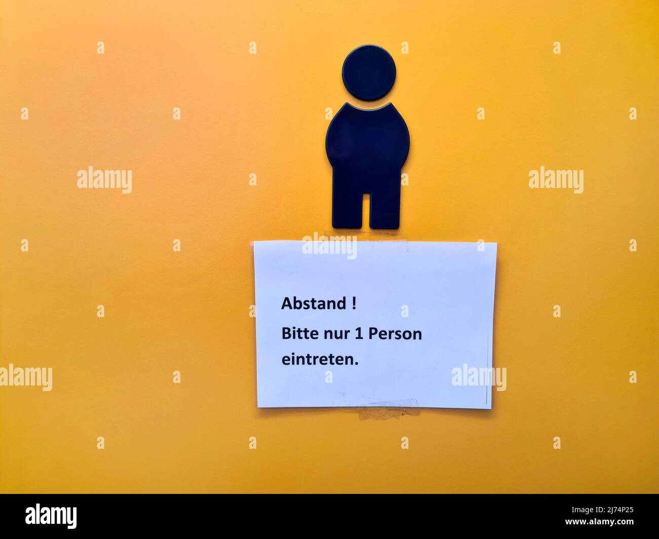 Note avec l'inscription « Distance! Veuillez entrer seulement 1 personnes' est accrochée sur la porte des toilettes de la chambre pour hommes, Allemagne Banque D'Images