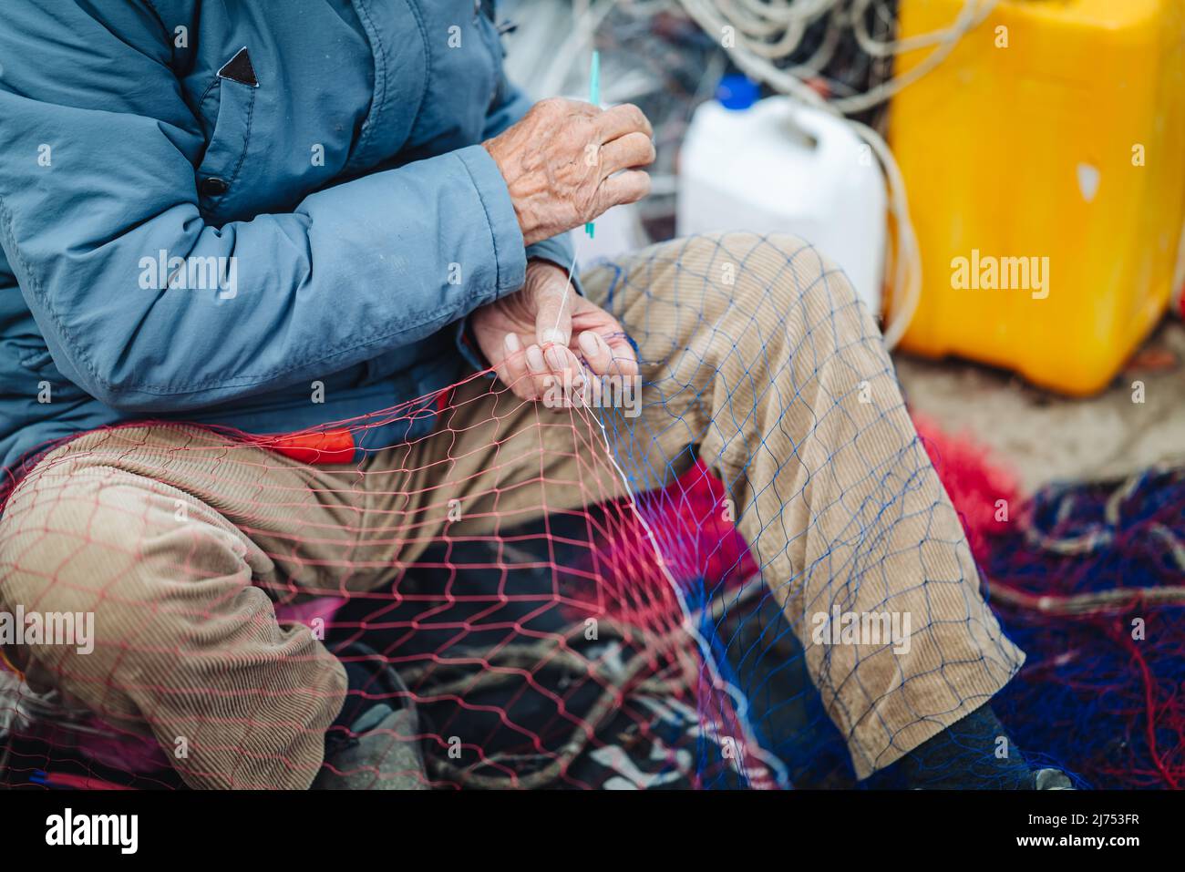 GALLIPOLI, ITALIE-AVRIL 2022 : pêcheurs locaux fixant le filet de pêche sur le quai Banque D'Images