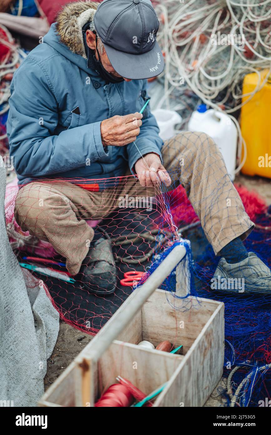 GALLIPOLI, ITALIE-AVRIL 2022 : pêcheurs locaux fixant le filet de pêche sur le quai Banque D'Images