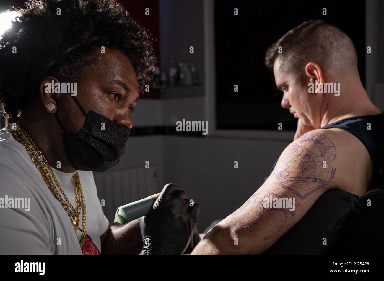 L'artiste professionnel américain de tatouage d'Afrique fait un tatouage sur le bras de client. Photographie de haute qualité. Banque D'Images