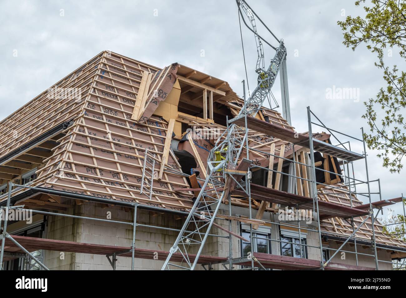 une grue de construction tordue est tombée dans la structure de toit nouvellement érigée Banque D'Images