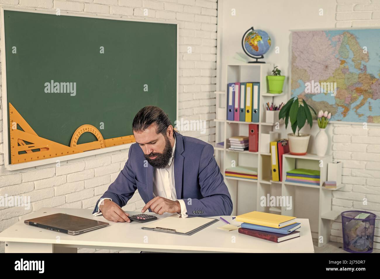 un homme barbu brutal travaille en classe avec une machine à calculer ...