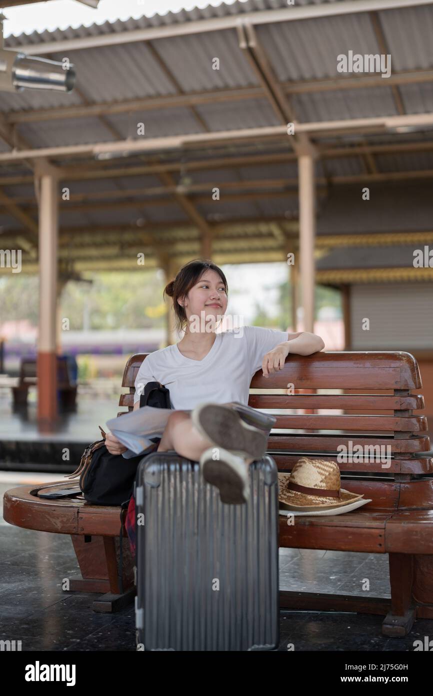 Bonne jeune femme asiatique voyageur ou routard à l'aide de la carte Choisissez où voyager avec des bagages à la gare, concept de voyage de vacances d'été Banque D'Images