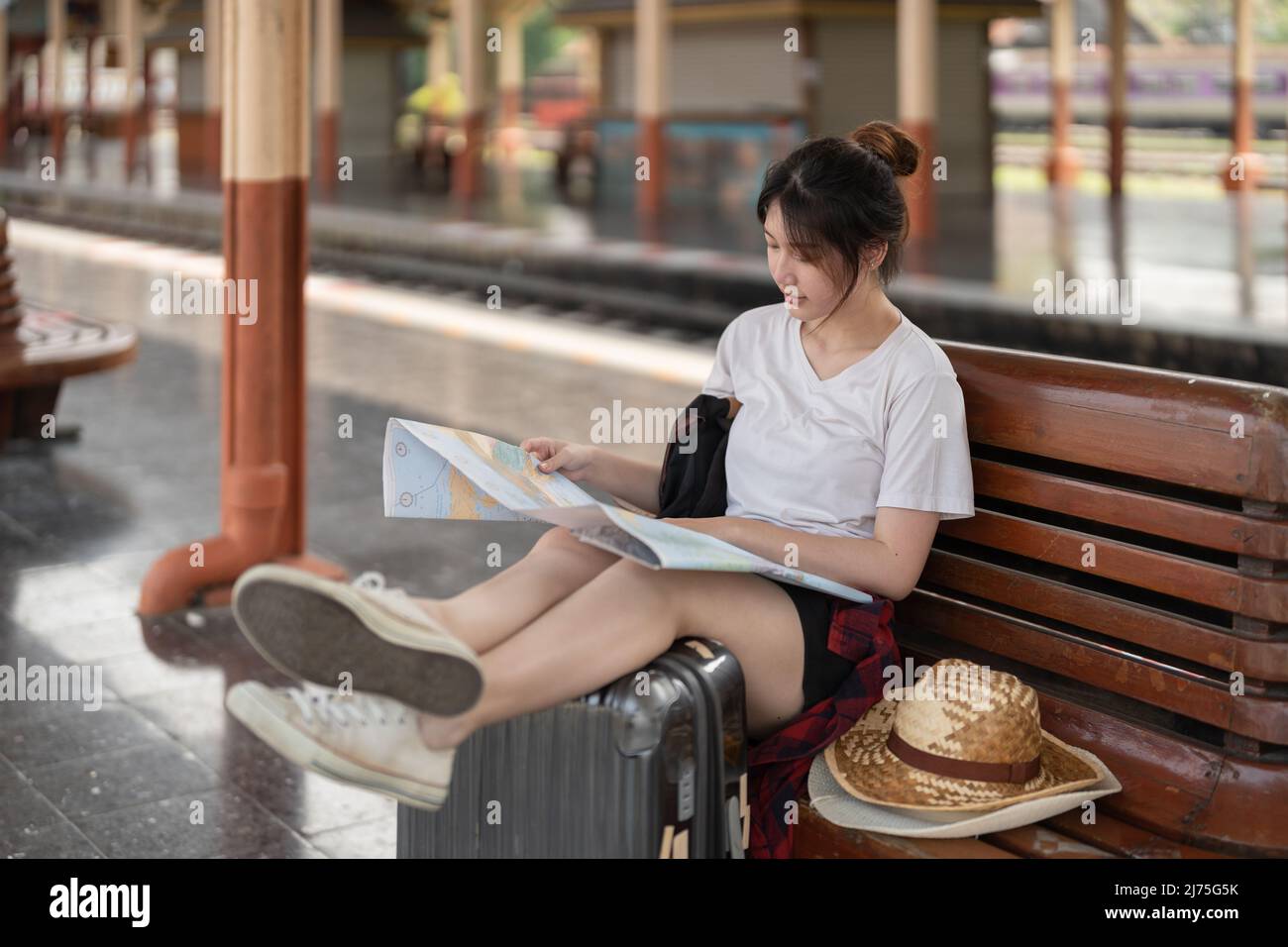 Bonne jeune femme asiatique voyageur ou routard à l'aide de la carte Choisissez où voyager avec des bagages à la gare, concept de voyage de vacances d'été Banque D'Images
