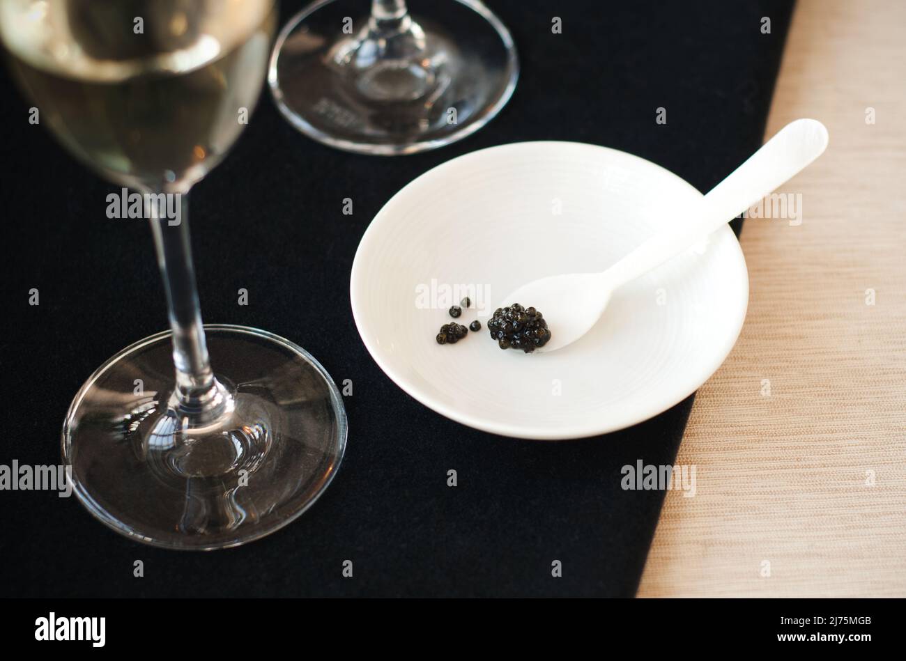 Cuillère avec caviar noir sur une assiette ; verre de champagne Banque D'Images